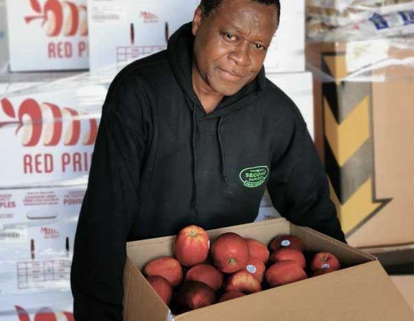 A man holding a box of apples.