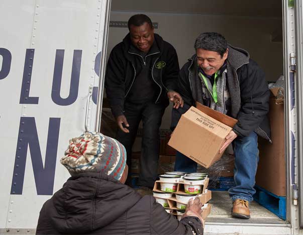 People on truck passing boxes of food to someone