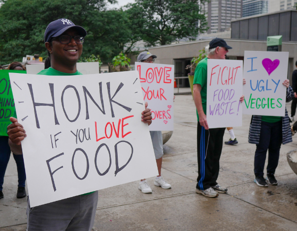 People holding up signs to protest against food waste.
